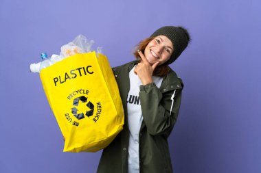 Genç Gürcü kız elinde plastik şişelerle dolu bir çanta tutarak mutlu ve gülümsüyor.