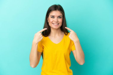 Mavi arka planda izole edilmiş beyaz bir kadın baş parmak işareti yapıyor.