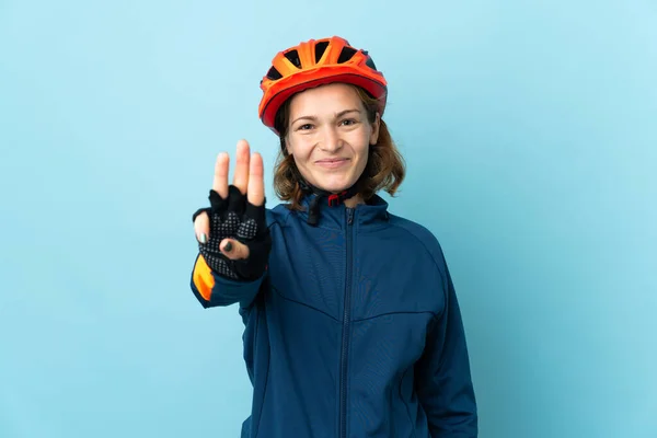 Молода Жінка Велосипедистка Ізольована Синьому Фоні Щаслива Рахує Трьох Пальцями — стокове фото