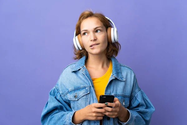 Młoda Gruzińska Kobieta Odizolowana Fioletowym Tle Słuchanie Muzyki Telefonu Komórkowego — Zdjęcie stockowe