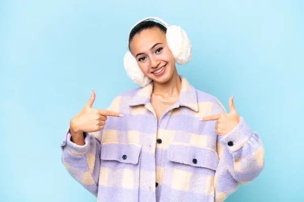 stock image Young Arab woman wearing winter muffs isolated on blue background proud and self-satisfied