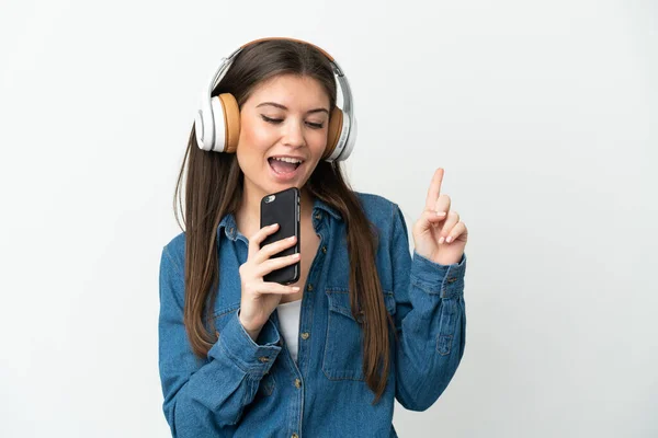 年轻的高加索女人被隔离在白人背景下 一边用手机一边听音乐 一边唱歌 — 图库照片