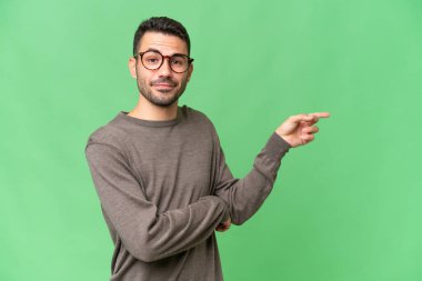 İzole edilmiş arka planda genç, yakışıklı beyaz bir adam parmak kaldırıyor.