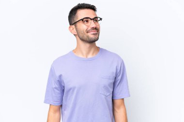 Beyaz arka planda izole edilmiş genç beyaz adam yukarı bakarken bir fikir düşünüyor.