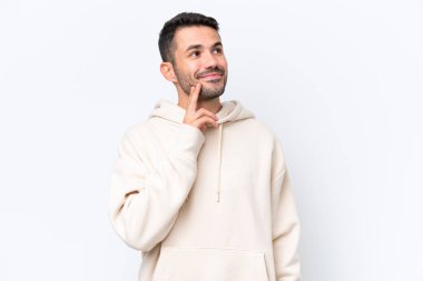 Beyaz arka planda izole edilmiş genç beyaz adam yukarı bakarken bir fikir düşünüyor.