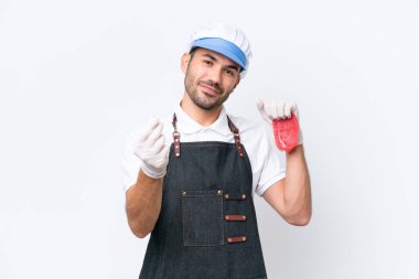 Kasap beyaz önlük takmış ve izole edilmiş beyaz arka planda taze et servis ediyor. Para hareketi yapıyor.