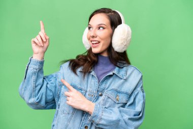 İzole edilmiş arka planda kışlık kuklalar takan beyaz bir kadın işaret parmağıyla işaret etmek harika bir fikir.