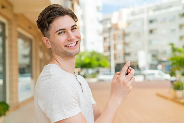 年轻英俊男子用手机发短信或发电子邮件 — 图库照片
