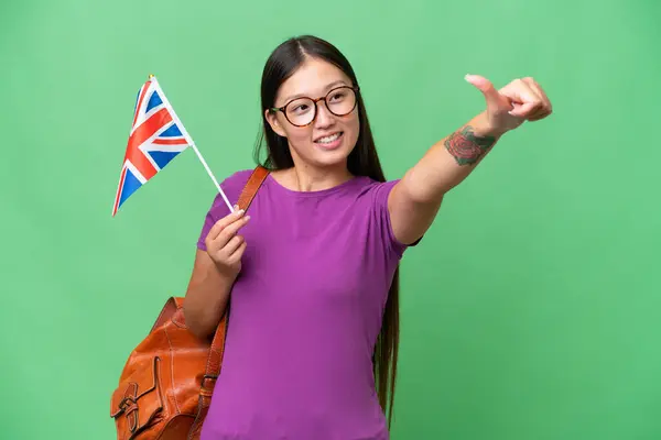 イギリスの国旗を背景に人差し伸べした若いアジア人女性が親指を立てて — ストック写真