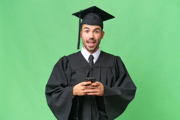 Jovem Graduado Universitário Sobre Fundo Isolado Surpreendido Enviando Uma Mensagem — Fotografia de Stock