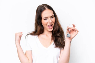 Beyaz arka planda zaferi kutlayan, elinde ev anahtarı tutan beyaz bir kadın.