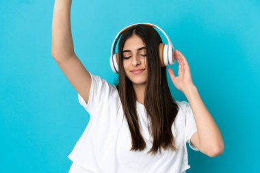 Genç beyaz kadın mavi arka planda izole edilmiş müzik ve dans dinliyor.