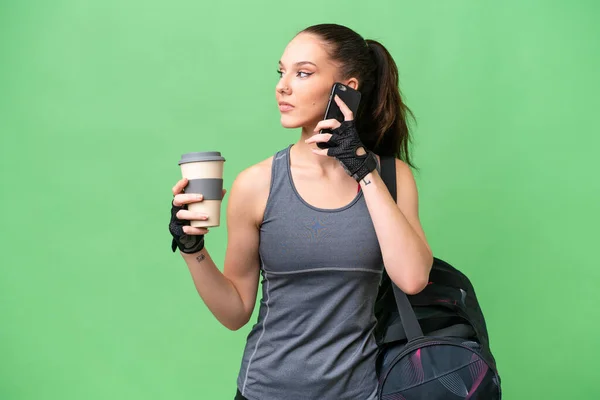 若いですスポーツ女性とともにスポーツバッグ上の隔離された背景保持コーヒーを取り去るためにと携帯電話 — ストック写真