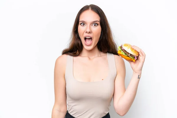 Młoda Kaukaska Kobieta Trzyma Hamburgera Białym Tle Zaskoczeniem Wstrząśniętym Wyrazem — Zdjęcie stockowe