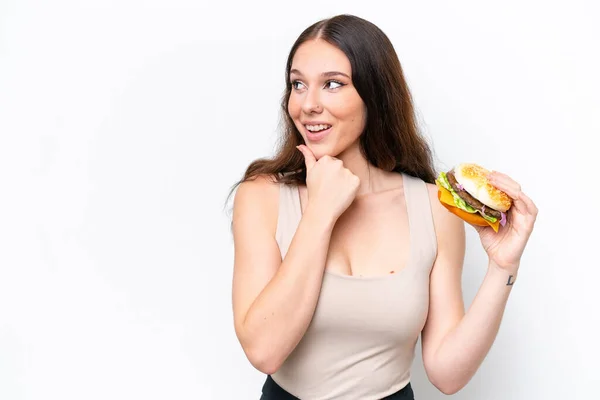 Young Caucasian Woman Holding Burger Isolated White Background Thinking Idea — Zdjęcie stockowe