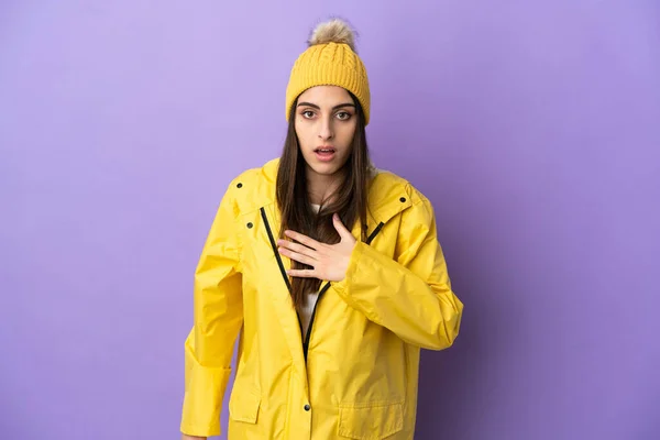 stock image Young caucasian woman wearing a rainproof coat isolated on purple background surprised and shocked while looking right