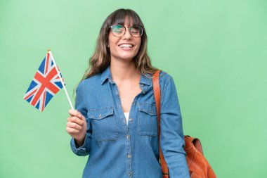 Young caucasian woman holding an United Kingdom flag over isolated background laughing