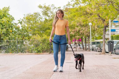 Dışarıda sevimli siyah köpeği olan genç sarışın kadın.