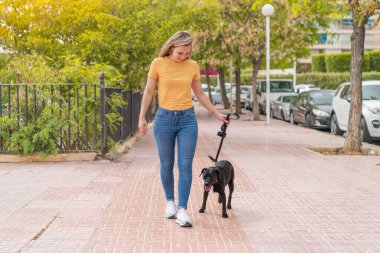 Dışarıda sevimli siyah köpeği olan genç sarışın kadın.