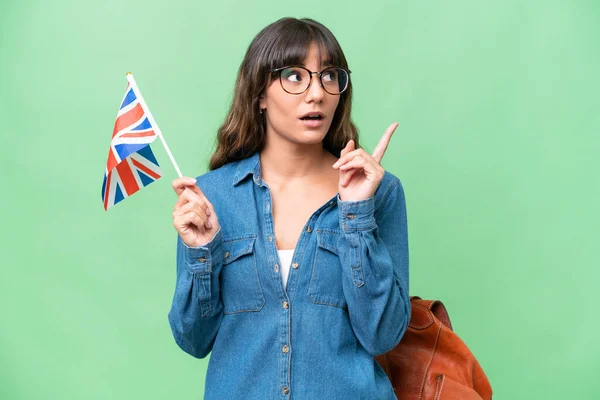 年轻的高加索女人在孤立的背景下举着英国国旗 想着指指点点 — 图库照片
