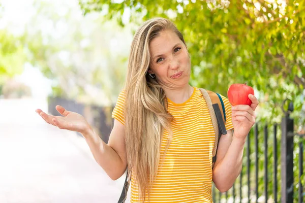 Junge Blonde Frau Mit Einem Apfel Freien Macht Zweifel Geste — Stockfoto