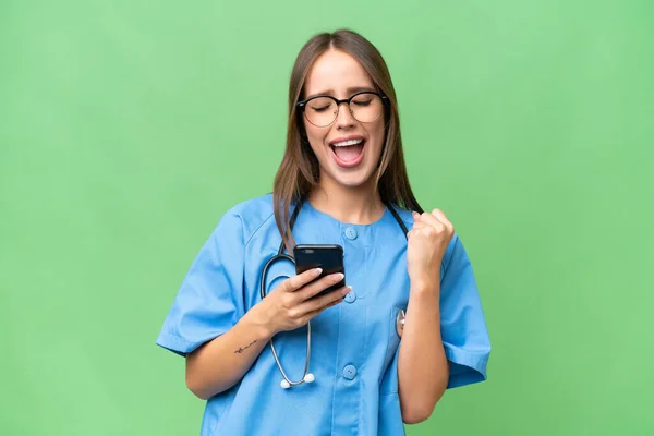 Junge Krankenschwester Kaukasische Frau Über Isolierten Hintergrund Mit Telefon Siegesposition — Stockfoto