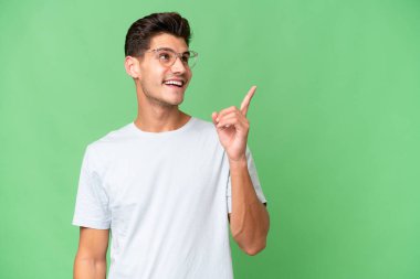 Young caucasian handsome man over isolated background intending to realizes the solution while lifting a finger up