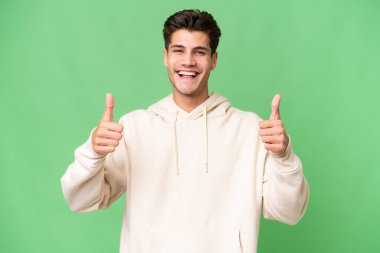 Young caucasian handsome man over isolated background giving a thumbs up gesture