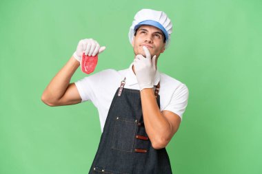 Kasap beyaz adam önlük takıyor ve soyutlanmış arka planda taze et servis ediyor.