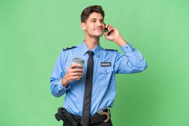Arka planda izole edilmiş genç bir polis kahve ve bir cep telefonu tutuyor.