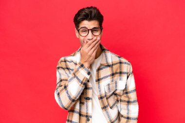 Genç, beyaz, yakışıklı, kırmızı arka planda izole edilmiş mutlu ve gülümseyen bir adam.