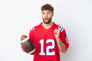 Beyaz arka planda ragbi oynayan beyaz tenli genç bir adam, bir fikir üzerinde parmak kaldırmayı düşünüyor.