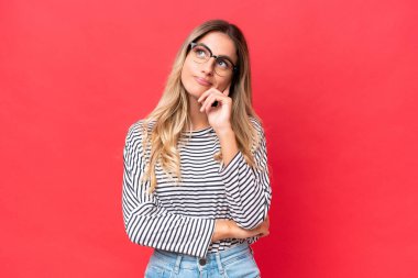 Genç Uruguaylı kadın kırmızı arka planda izole edilmiş. Şüpheleri ve düşünceleri var.