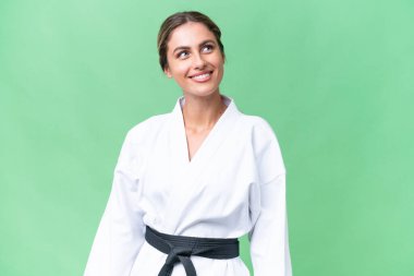 Genç Uruguaylı kadın izole edilmiş arka planda karate yapıyor. Yukarı bakarken bir fikir düşünüyor.
