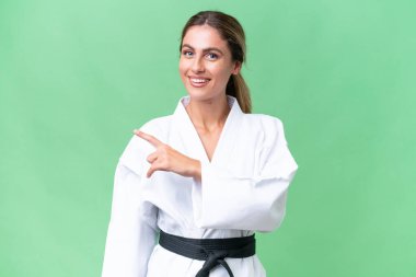 Genç Uruguaylı kadın tecrit edilmiş arka planda karate yapıyor. Ürünü sunmak için yan tarafa bakıyor.