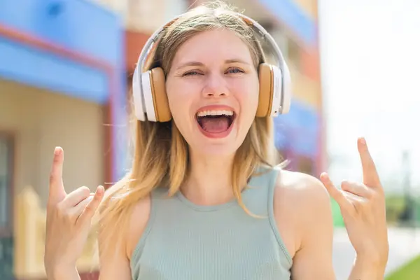 Молодая Блондинка Открытом Воздухе Слушает Музыку Делая Рок Жест — стоковое фото