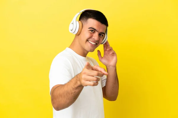 Молодий Красивий Чоловік Над Ізольованим Жовтим Тлом Слухає Музику Вказує — стокове фото