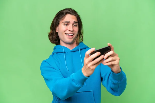 年轻英俊男子被隔离在绿色的背景下玩手机 — 图库照片