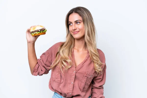 Młoda Ładna Urugwajska Kobieta Trzyma Hamburgera Odizolowany Białym Tle Happy — Zdjęcie stockowe