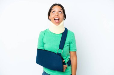 Boyunluk takan genç İspanyol kadın beyaz arka planda izole edilmiş bir şekilde yukarı bakıyor ve şaşırmış bir ifadeyle