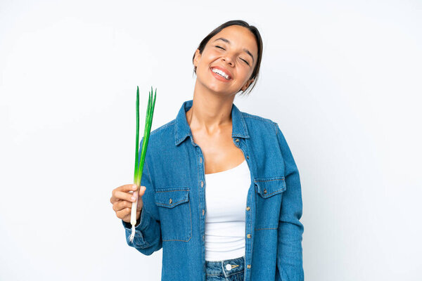 Young hispanic woman holding chive isolated on white background laughing