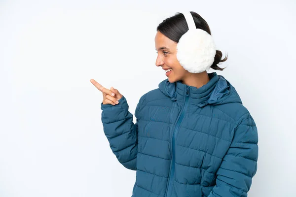 年轻的惊慌失措的女人戴着冬季的耳罩 被白色背景隔离 手指指向侧面 并展示了一种产品 — 图库照片