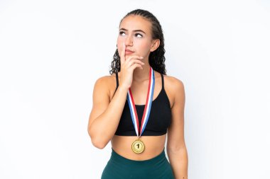 Beyaz arka planda madalyaları olan genç sporcu kadının şüpheleri ve şaşkın bir yüz ifadesi var.