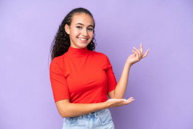 Mor arka planda izole edilmiş genç bir kadın davet edilmek için ellerini yana uzatıyor.