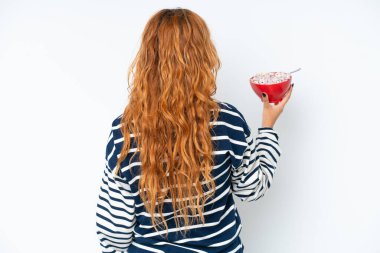 Beyaz arka planda, kahvaltı sütü içen beyaz tenli genç bir kadın.