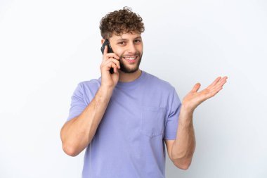 Beyaz arka planda izole edilmiş yakışıklı beyaz bir adam cep telefonuyla sohbet ediyor.