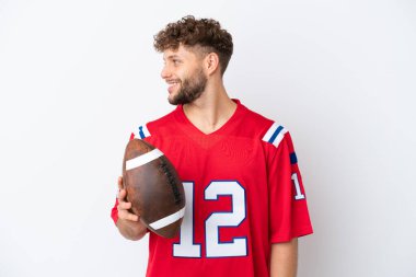 Beyaz arka planda ragbi oynayan beyaz tenli genç bir adam.