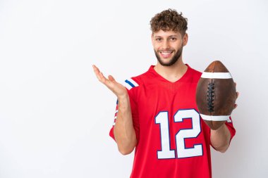 Rugby oynayan beyaz tenli genç adam, beyaz arka planda izole edilmiş ve davet edilmek için ellerini yana uzatıyor.