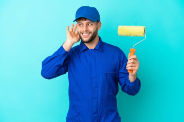 Kafkasyalı ressam, mavi arka planda izole edilmiş bir şekilde elini kulağına koyarak bir şeyler dinliyor.