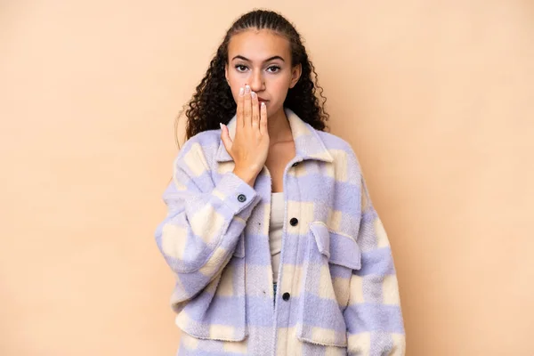 stock image Young woman isolated on beige background covering mouth with hand